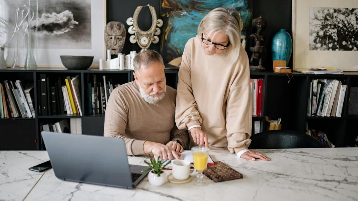 Elderly couple working together on a laptop in a cozy home office setting.