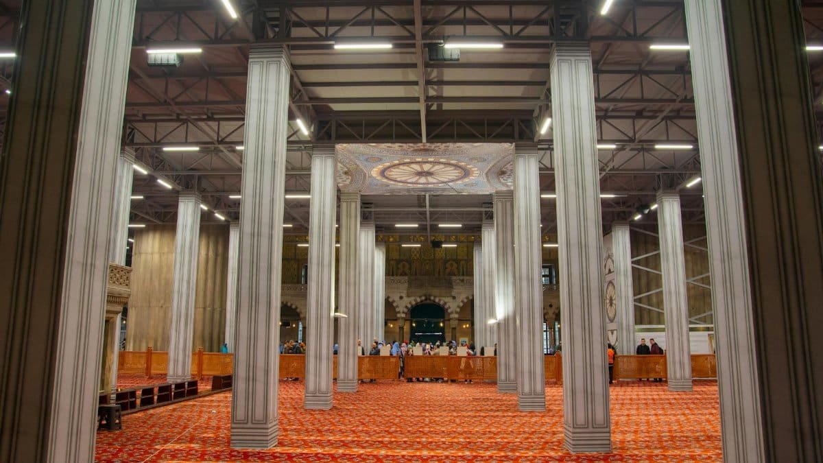 Stunning interior view of a grand mosque featuring decorative columns and intricate carpets.