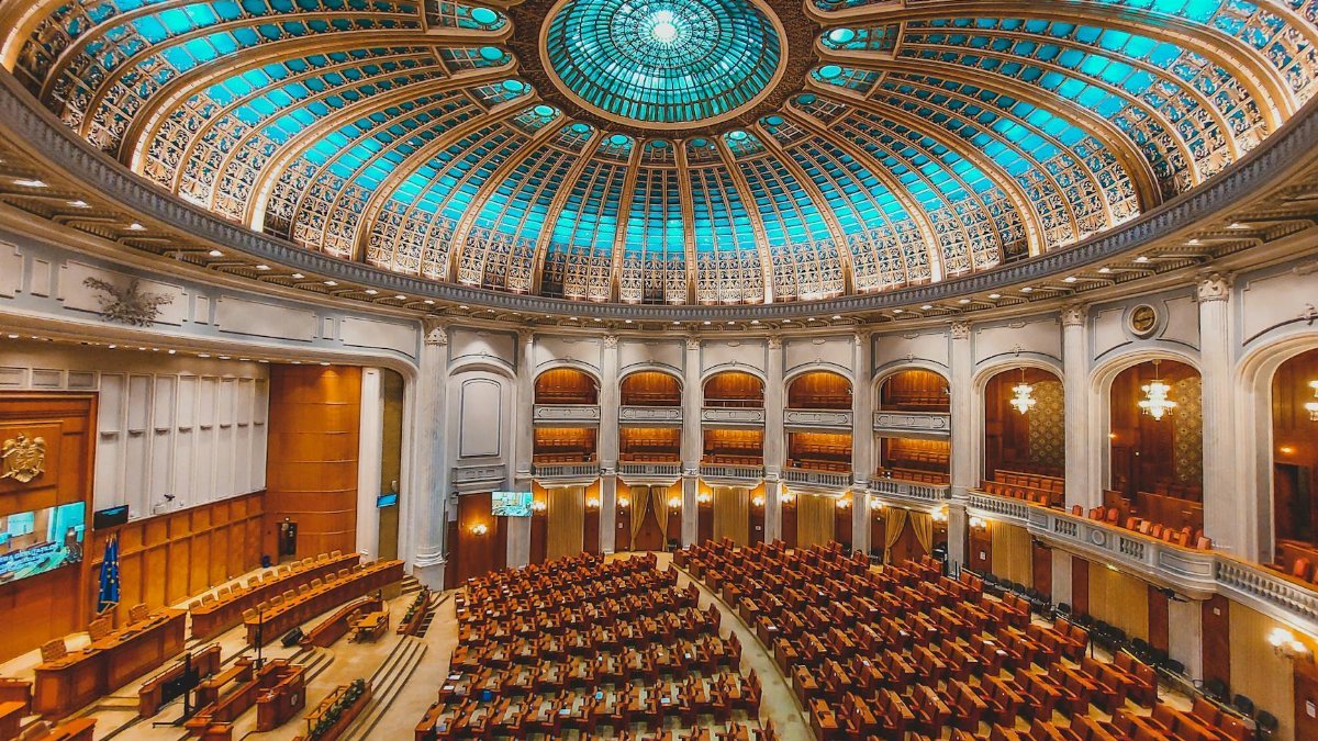 Vibrant interior of a parliament hall with a grand dome and intricate architecture.
