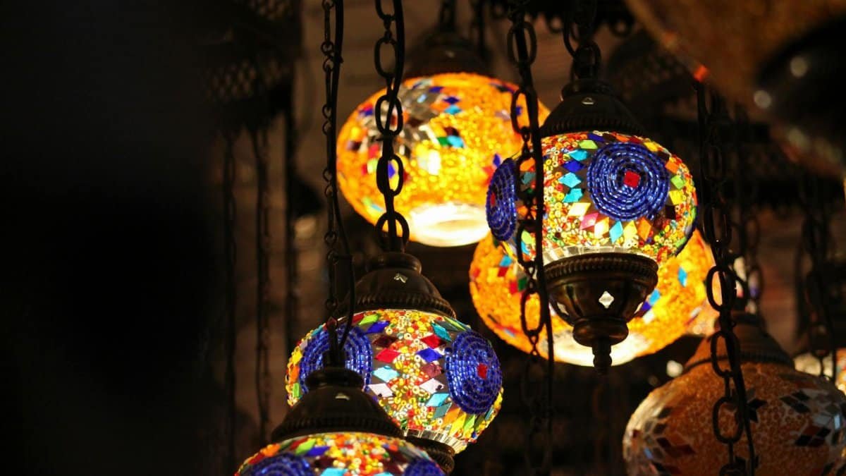 Colorful mosaic glass lamps hanging in a Dhaka market, illuminating the space with warmth.