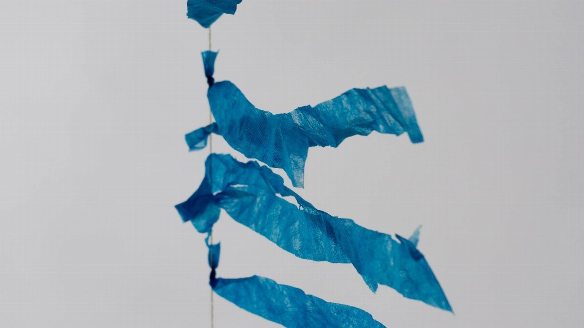 Close-up of blue streamers against a grey sky, capturing movement and whimsy.