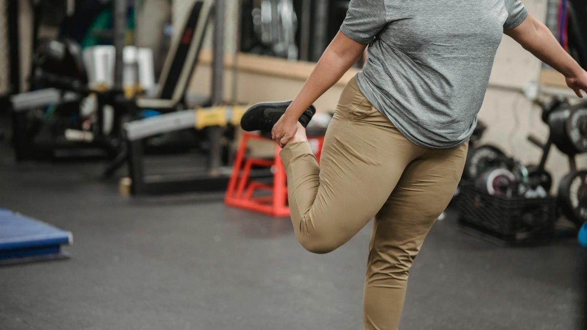 A plus size woman stretches in a gym, focusing on fitness and wellbeing.