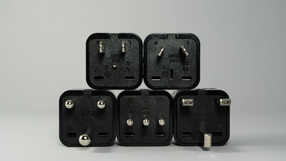A collection of various black international power plug adapters for global electronics use.