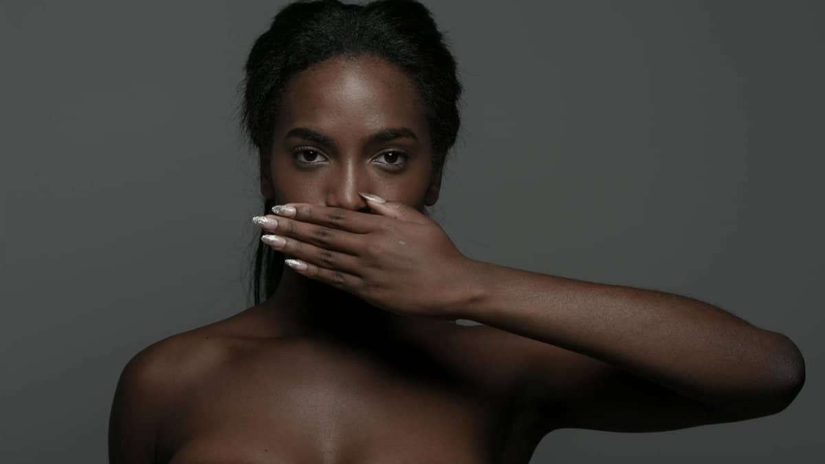 Thought-provoking portrait of a woman covering her mouth, exploring themes of silence and expression.