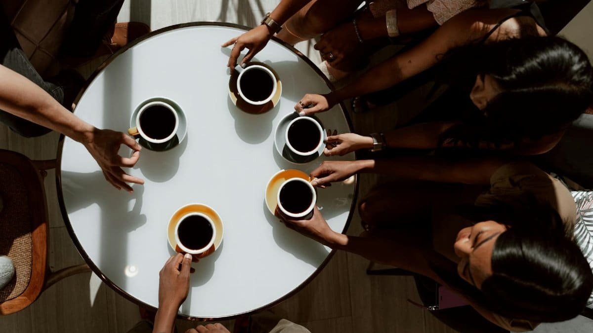 Group of friends gathered around a table, sharing coffee in a cozy setting.