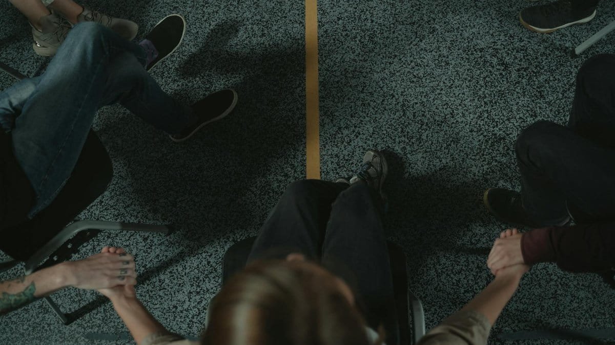 A diverse group of people holding hands in a circle, symbolizing support and unity in a mental health session.
