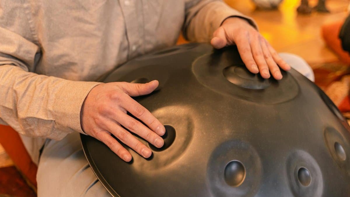 A person plays a handpan instrument, focusing on relaxation and zen vibes indoors.