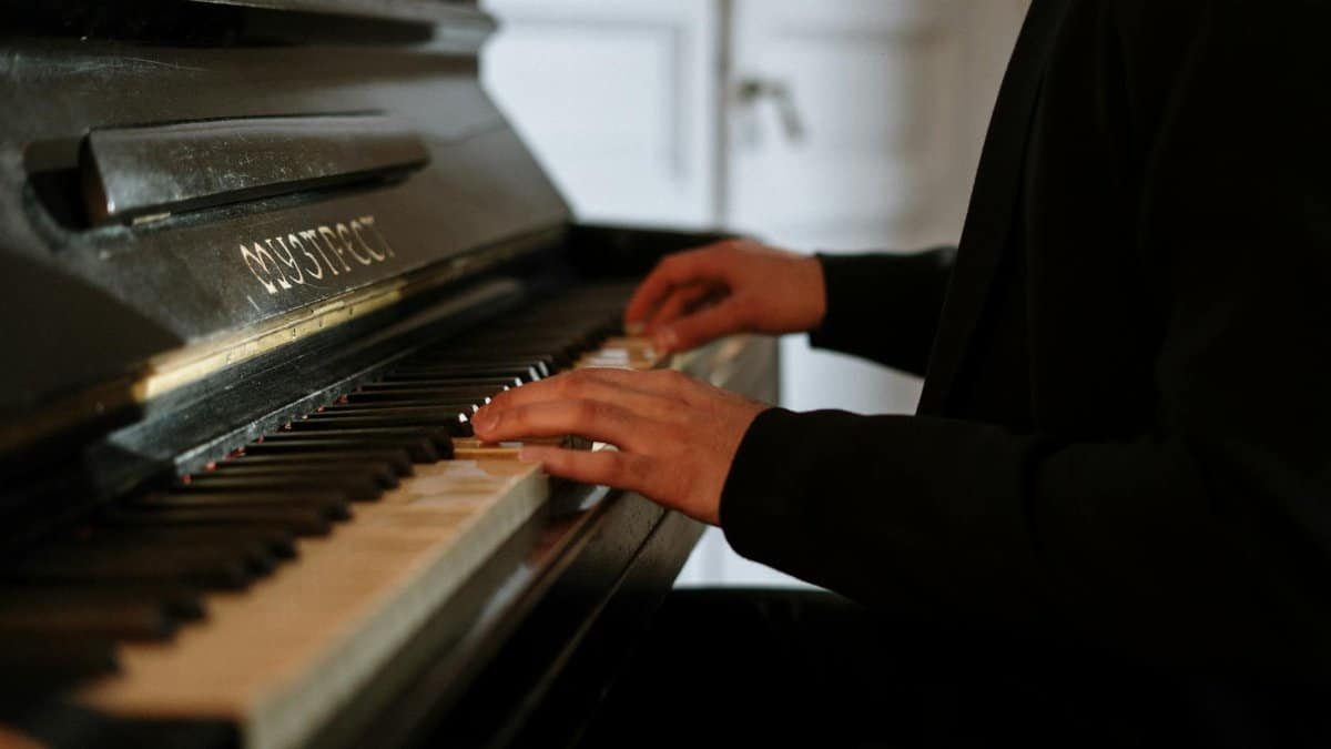 A close-up of hands playing the piano indoors, creating a cozy and intimate atmosphere.