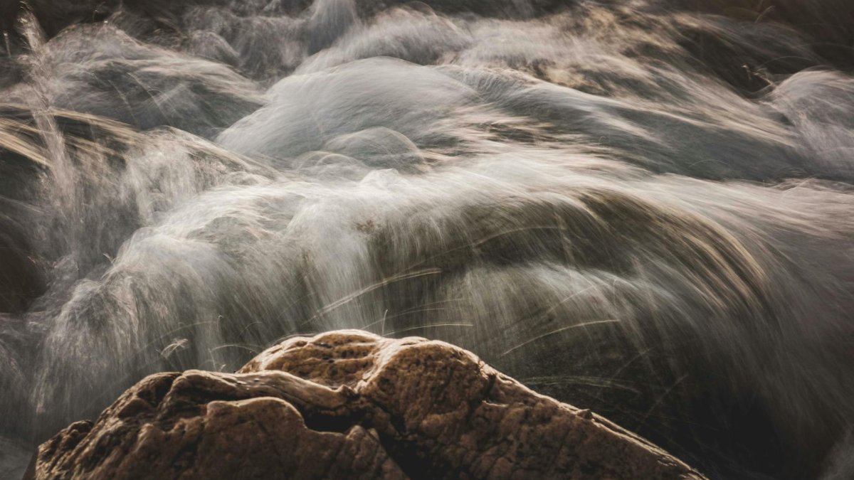 Dreamy long exposure shot of a river flowing over rocks, capturing the dynamic movement of water.