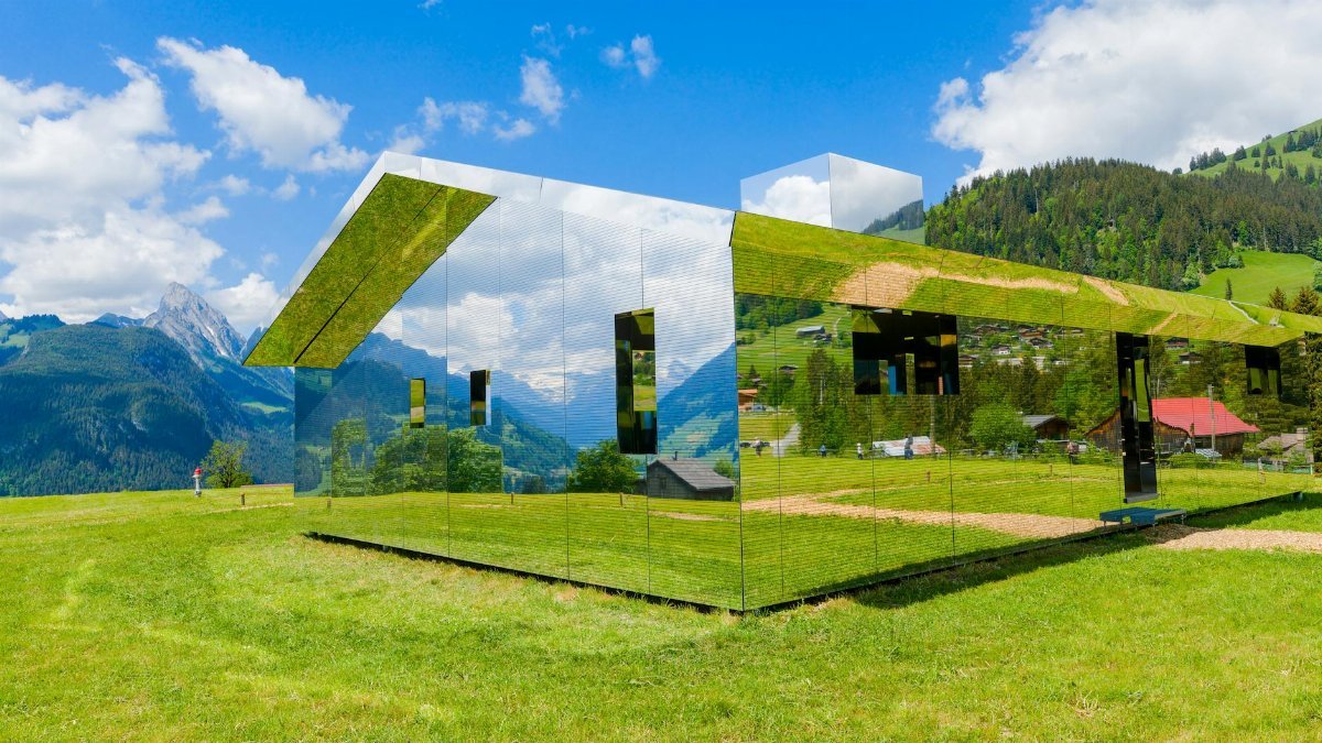 Modern reflective building in scenic Swiss Alps landscape in Saanen.