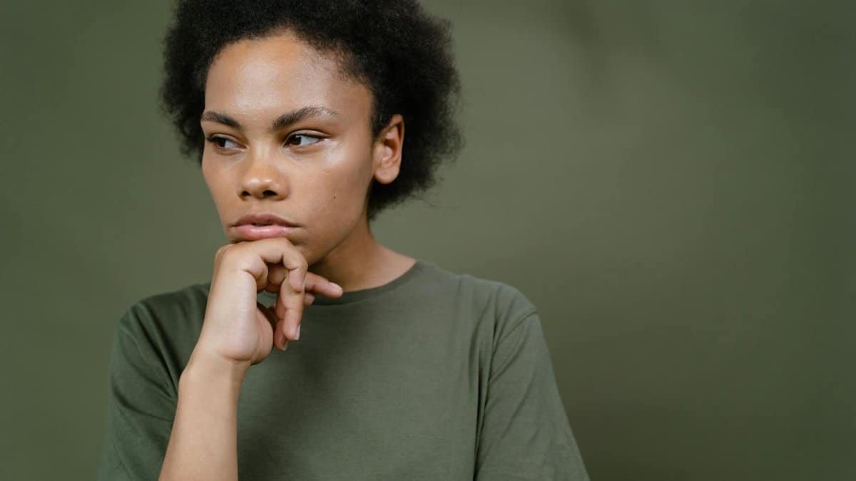 A pensive young woman with afro hair contemplating and looking away, emphasizing individuality and emotion.