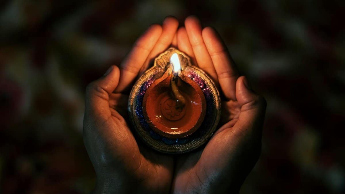 Top view of crop anonymous person demonstrating small bright candle burning in dark evening in soft focus