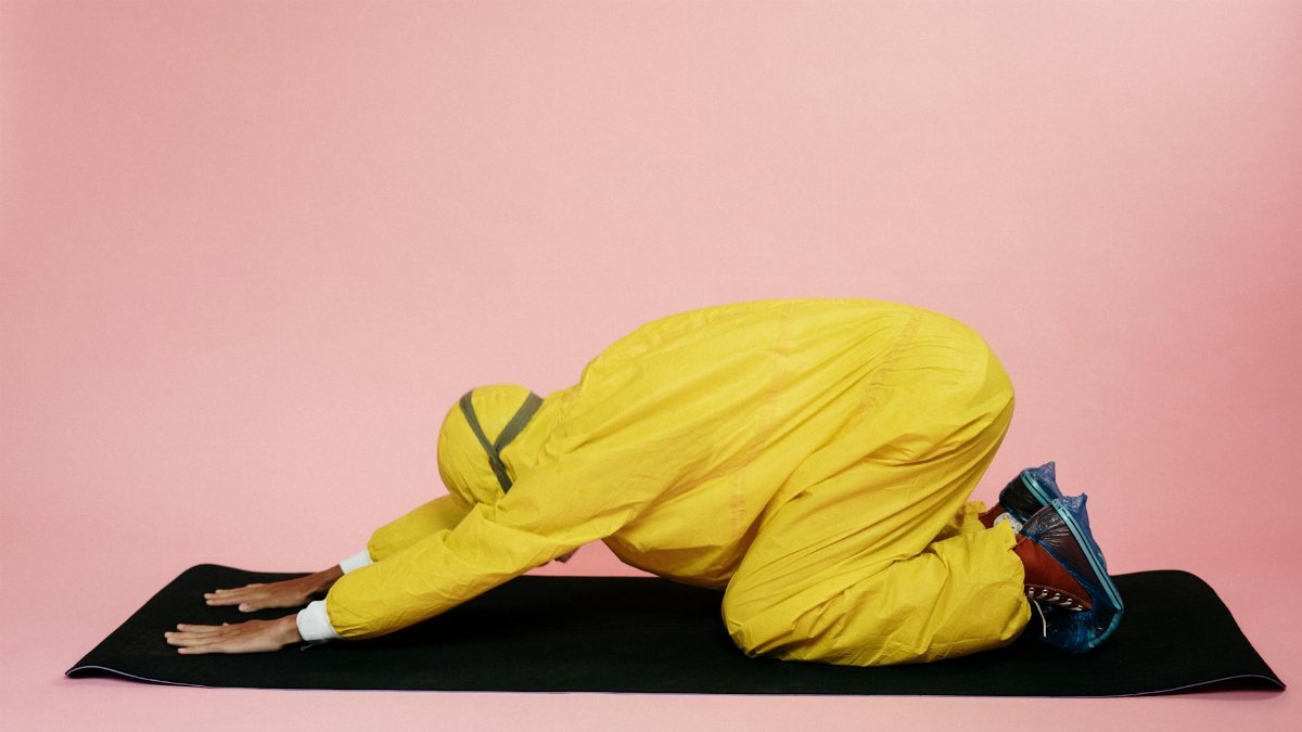 Person in protective gear performing yoga on a mat; a blending of health and safety themes.