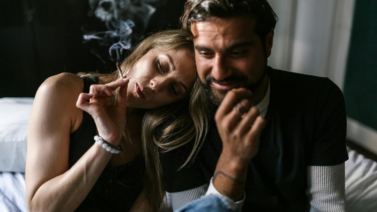 A couple enjoying a relaxed moment indoors while smoking a joint together.