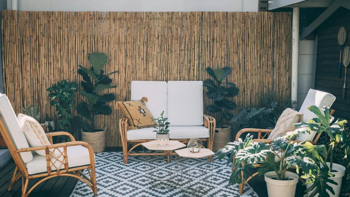 Serene outdoor patio featuring rattan furniture, potted plants, and bamboo decor.