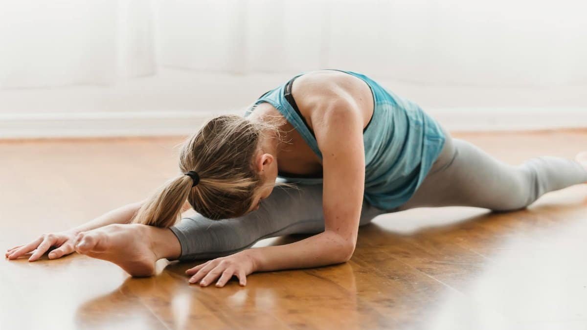 A woman practicing a yoga stretch indoors showcasing flexibility and focus.
