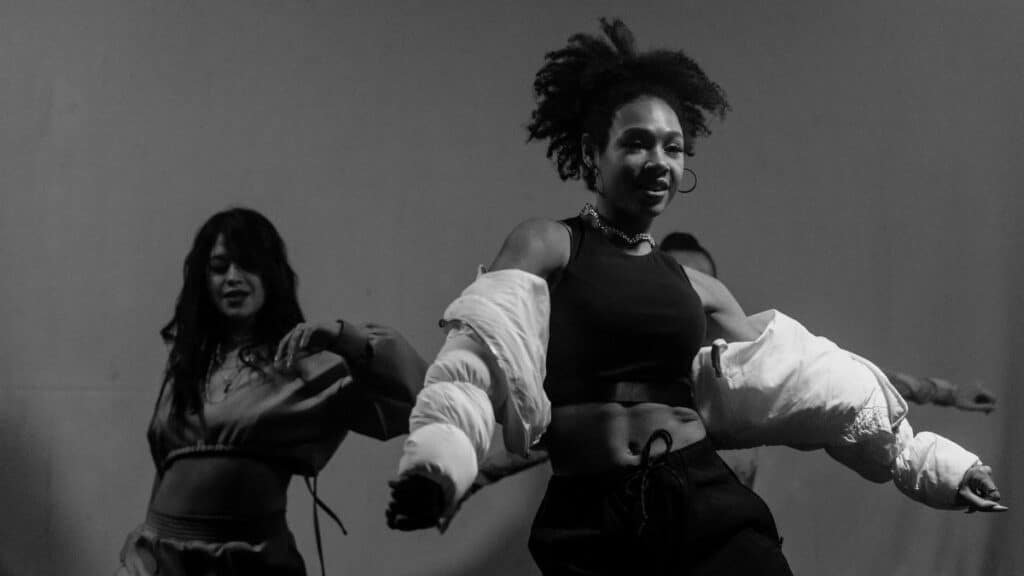 Captivating black and white photo of women dancing energetically indoors.