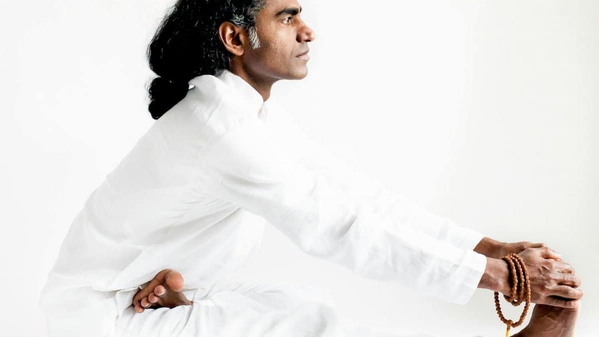 An Indian yogi practices seated forward bend asana, embodying mindfulness and calm.