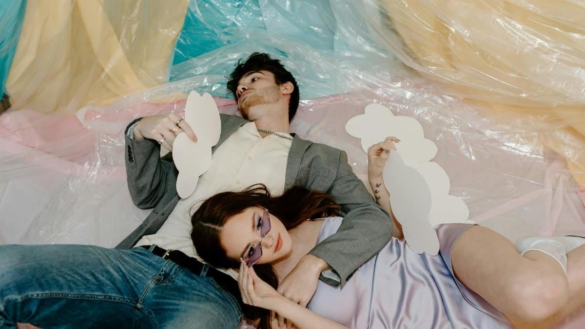 A couple relaxing indoors with creative paper clouds and colorful backdrop, embracing tranquility.
