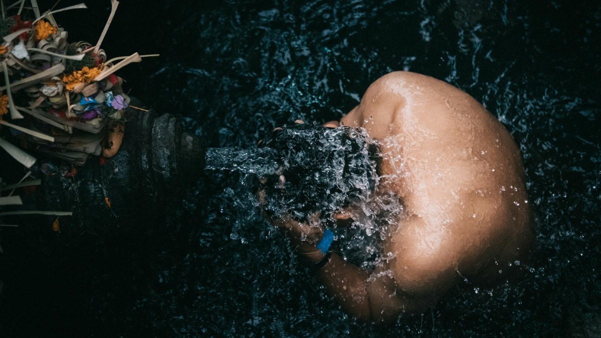 A man engaging in a spiritual cleansing ritual at a water site.