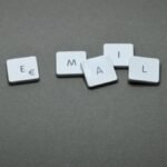 Close-up of the word 'email' formed with letter tiles on a gray surface.