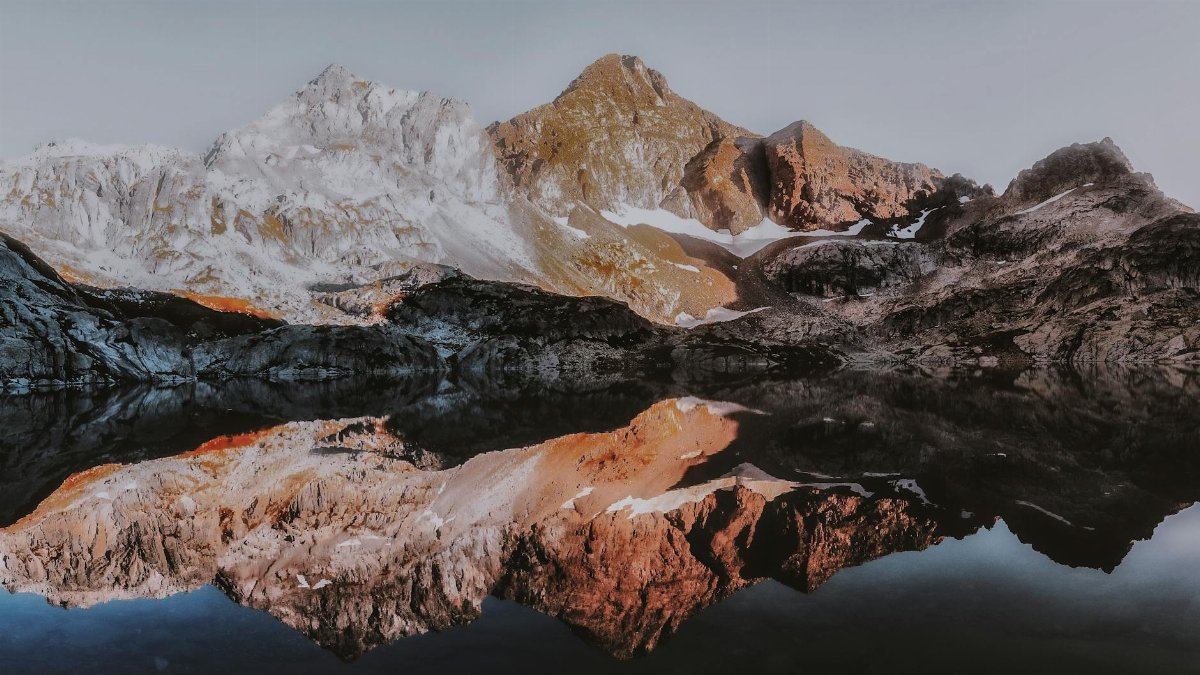 Stunning mountain landscape with snow-capped peaks reflecting in a calm lake, showcasing nature's serenity.