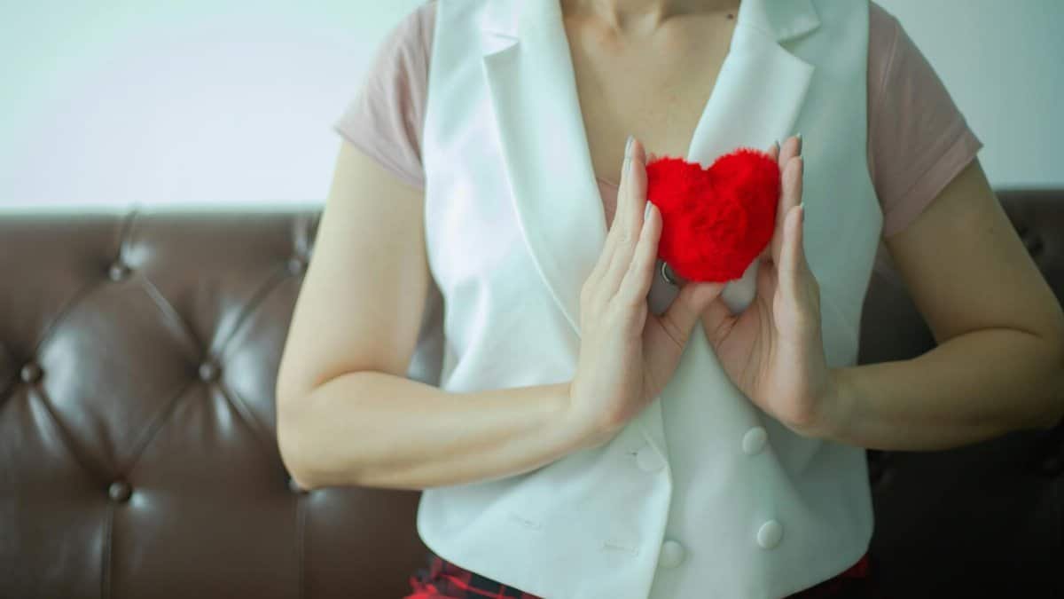 Close-up of woman holding a red heart-shaped plush, symbolizing love and care.