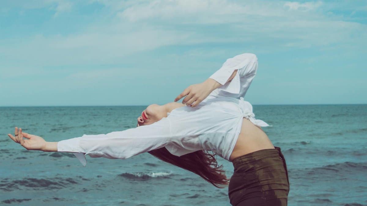 A woman performing a yoga pose by the ocean, capturing a moment of balance and tranquility.