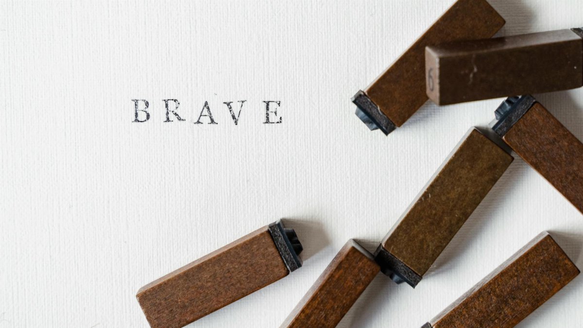Detailed image of the word 'Brave' stamped on paper with ink stamps beside it.