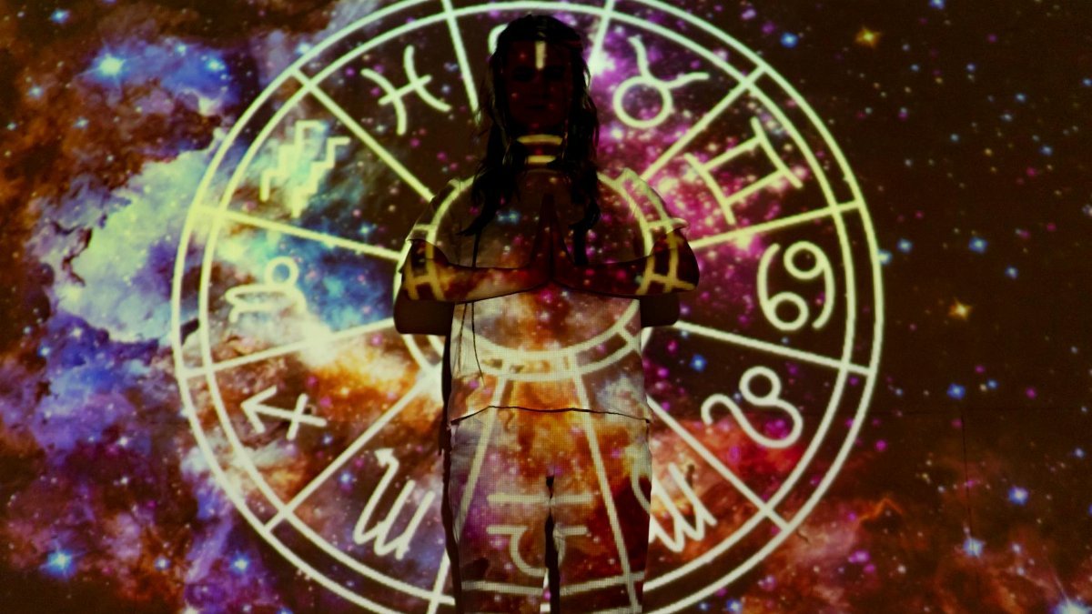 Silhouette of a person with celestial astrology symbols against a cosmic background.