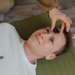 A man lying down during a crystal healing ritual indoors on a yoga mat.