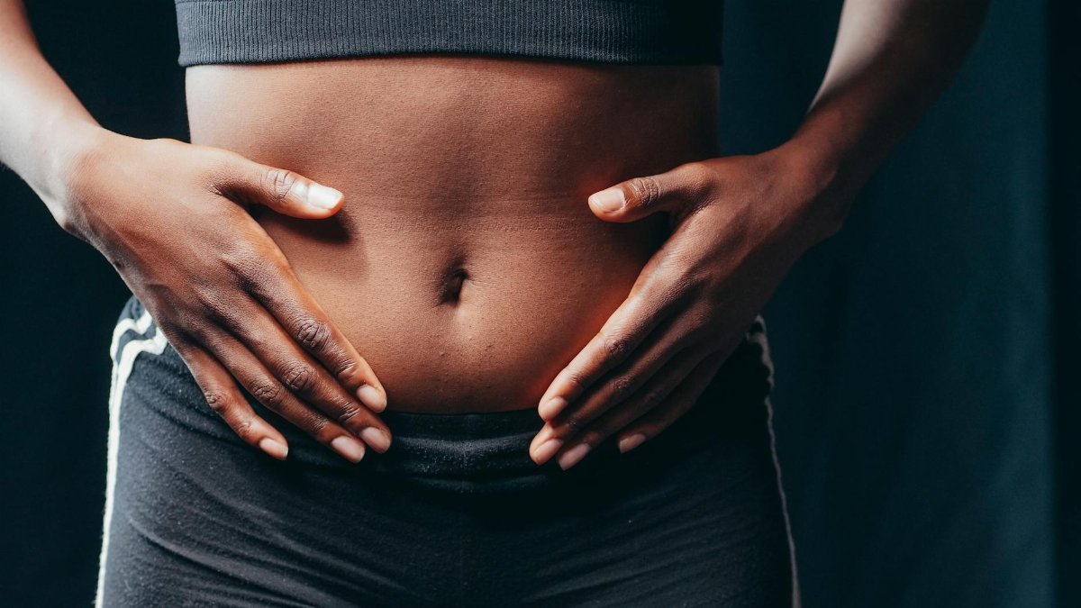 Close-up image of hands on abdomen signifying wellness, body awareness, or health check.