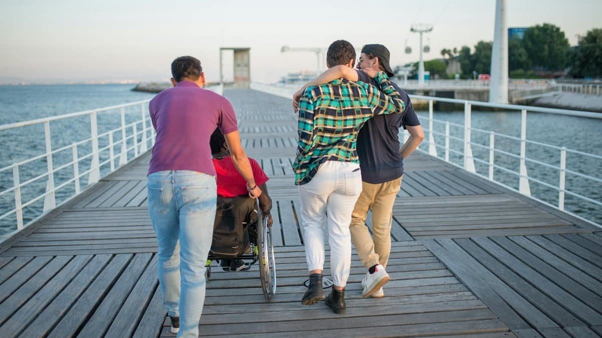 Group of friends walking along a scenic boardwalk by the sea, promoting friendship and accessibility.
