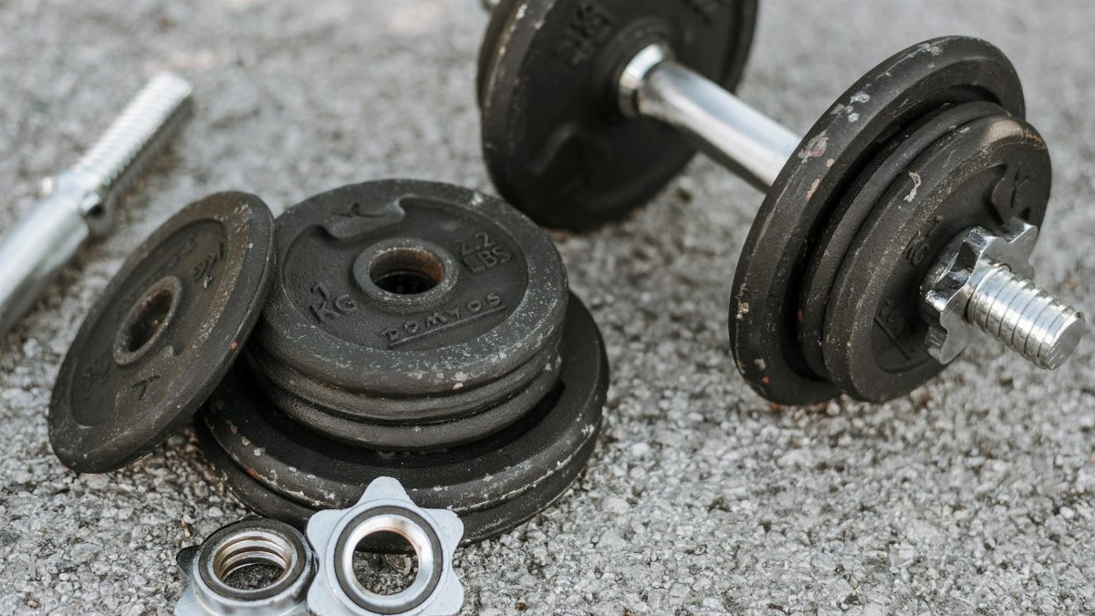 Black iron dumbbells on a paved ground, perfect for outdoor strength training and fitness routines.
