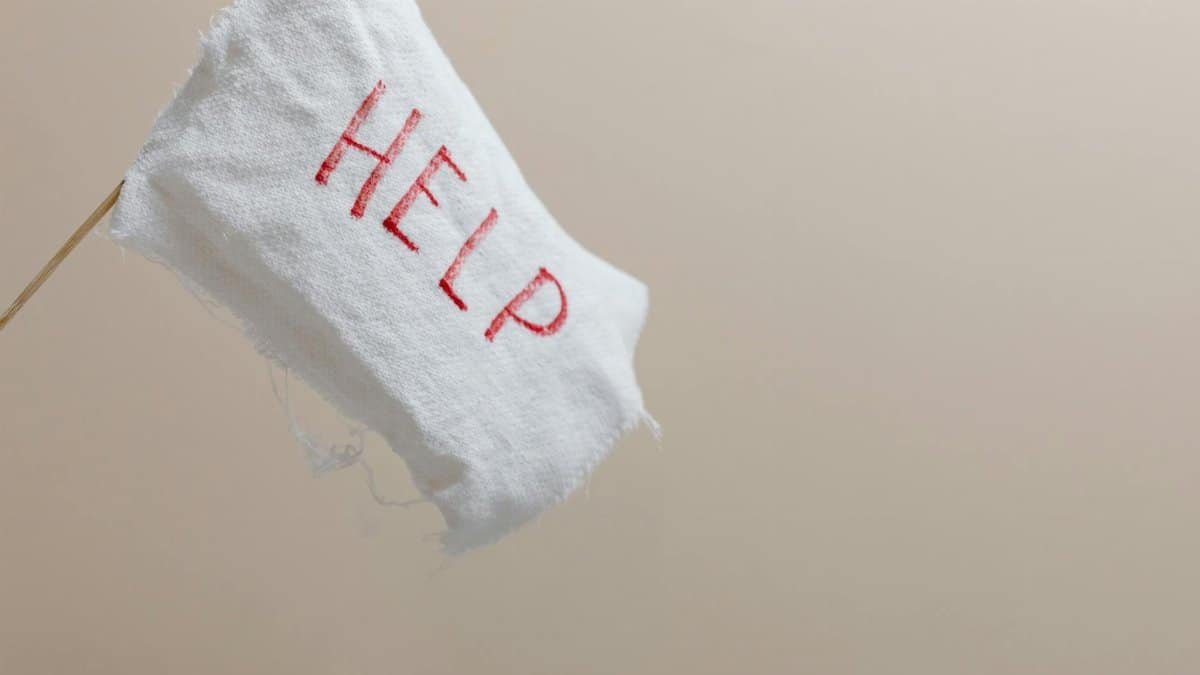 A white flag with 'HELP' displayed on a beige background, symbolic of seeking assistance.