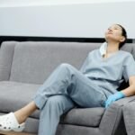 Nurse in scrubs takes a break, resting on a comfy hospital couch after a long shift.