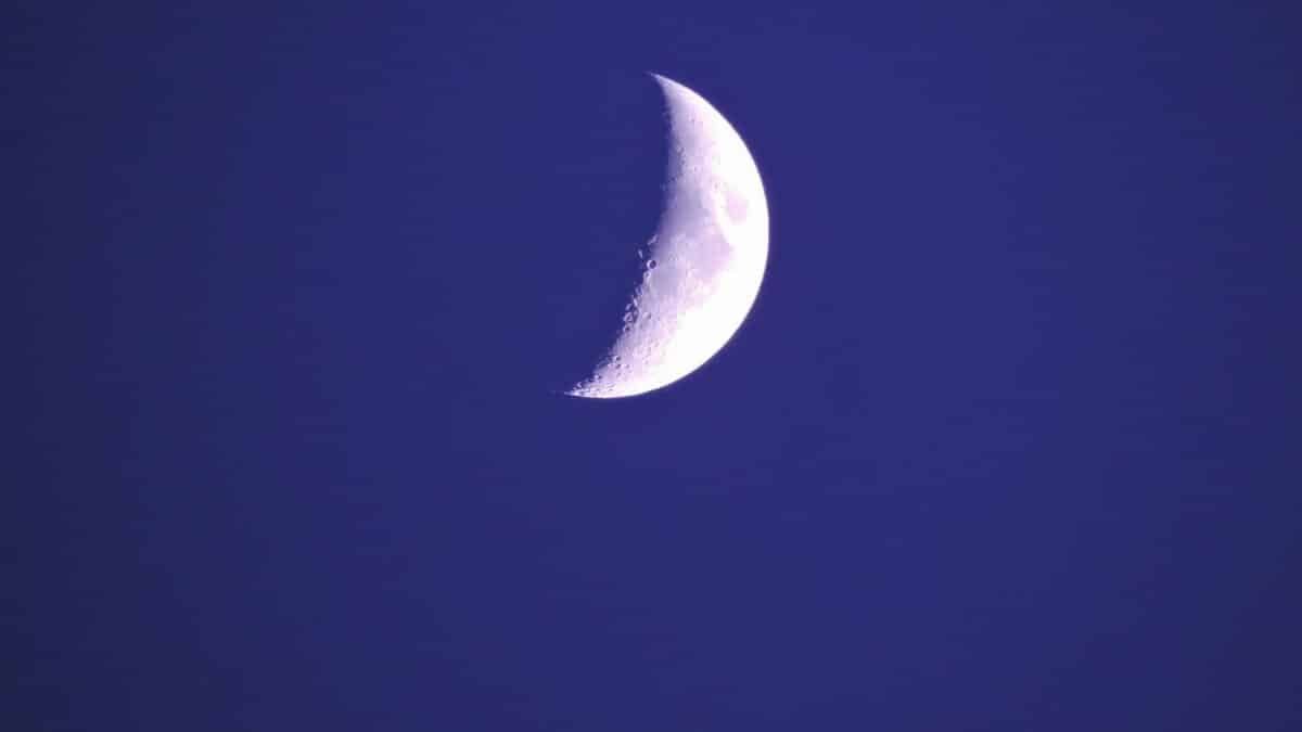 A clear, luminous crescent moon photographed in a deep blue night sky.