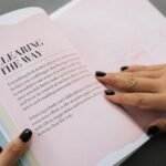 Hands flipping through a motivational book indoors, promoting clarity and wisdom.