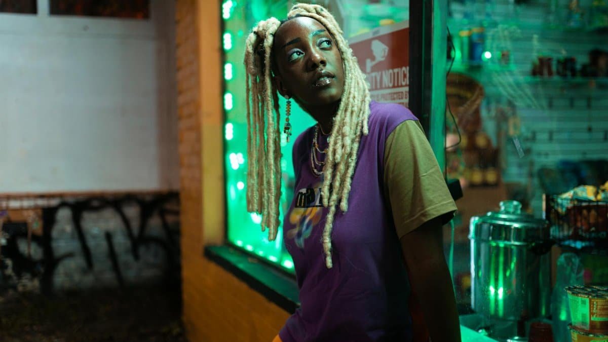 A fashionable woman with blonde locs posing at night in Atlanta street setting.