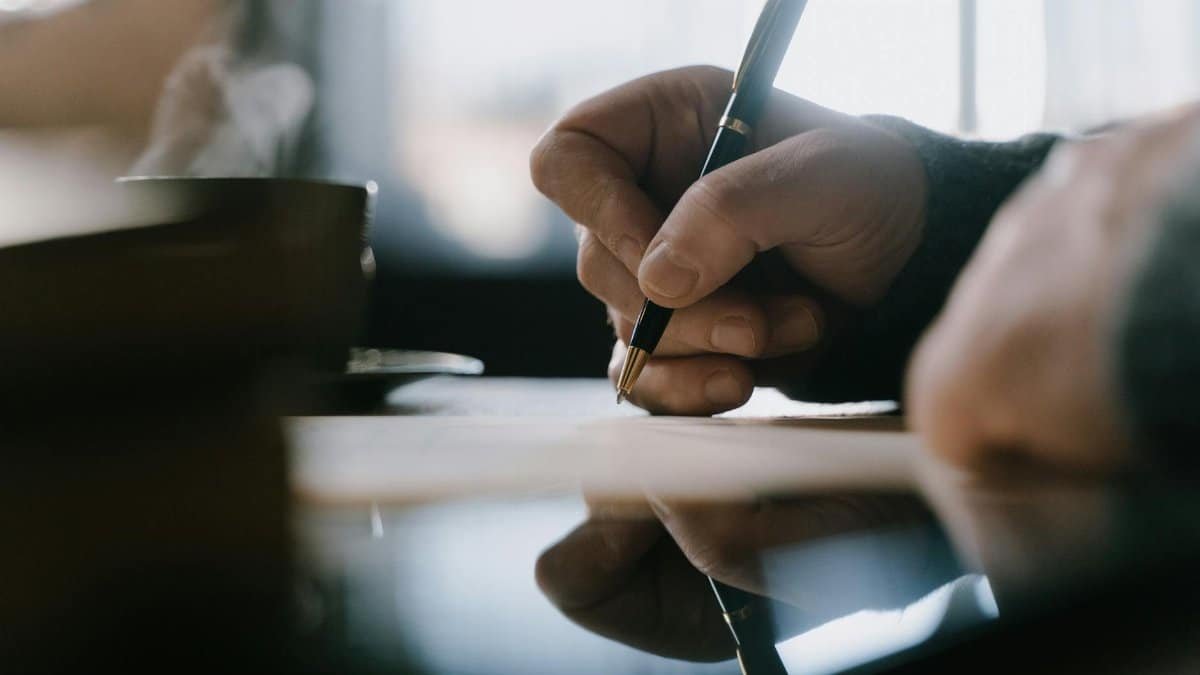 Focused adult hand writing with pen in a notebook, capturing creativity and concentration indoors.