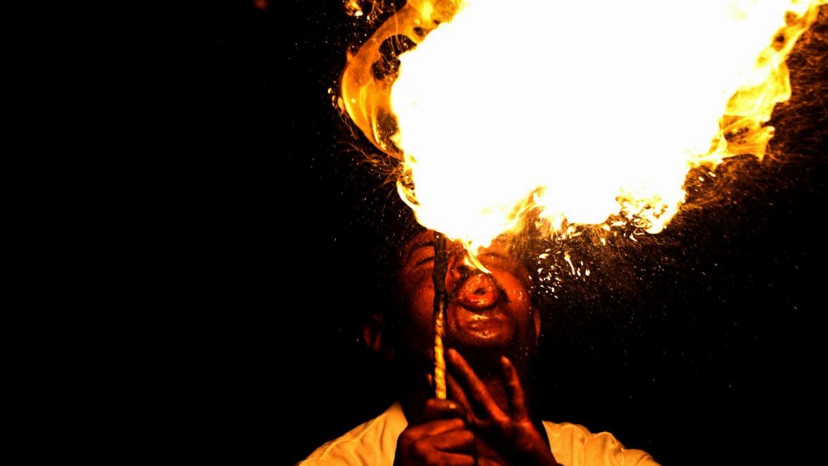 A mesmerizing display of fire breathing by a performer at night, showcasing artistic talent.
