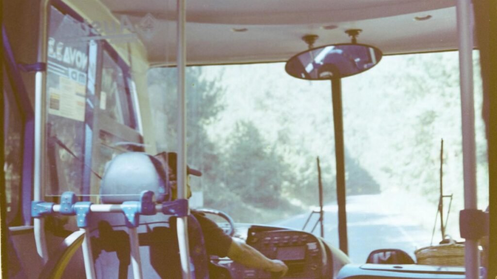 Interior view of a bus driving on a sunny day through a scenic countryside road.