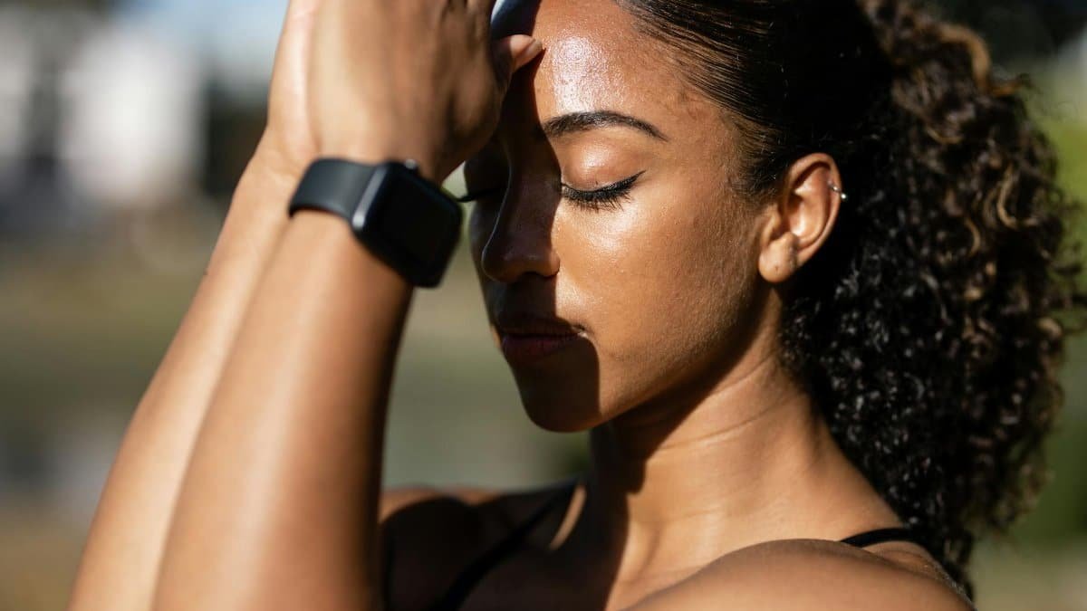 A woman meditates outdoors with eyes closed, embodying tranquility and focus.