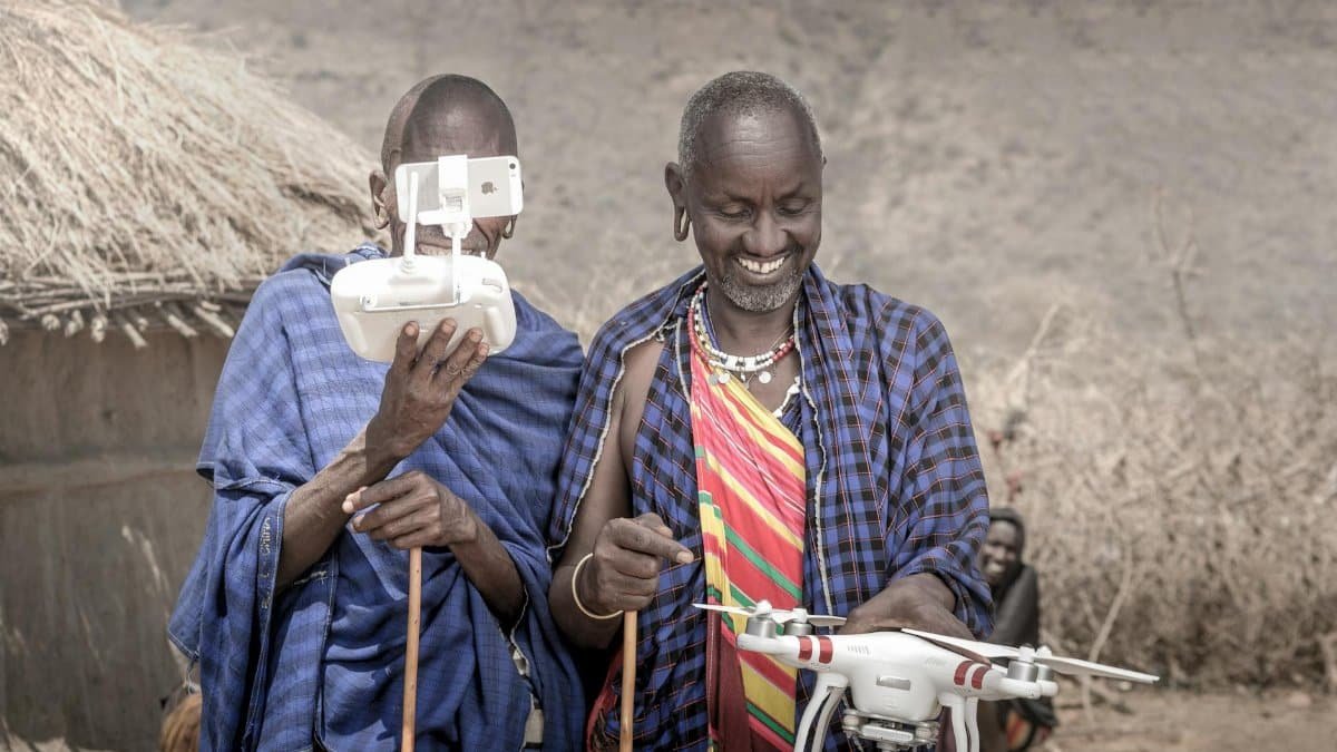 Maasai men wearing traditional clothing operate a drone in Arusha, Tanzania, blending tradition with technology.
