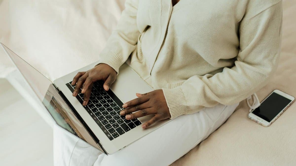 Person working remotely on laptop with smartphone nearby. Cozy home setting, lifestyle focus.