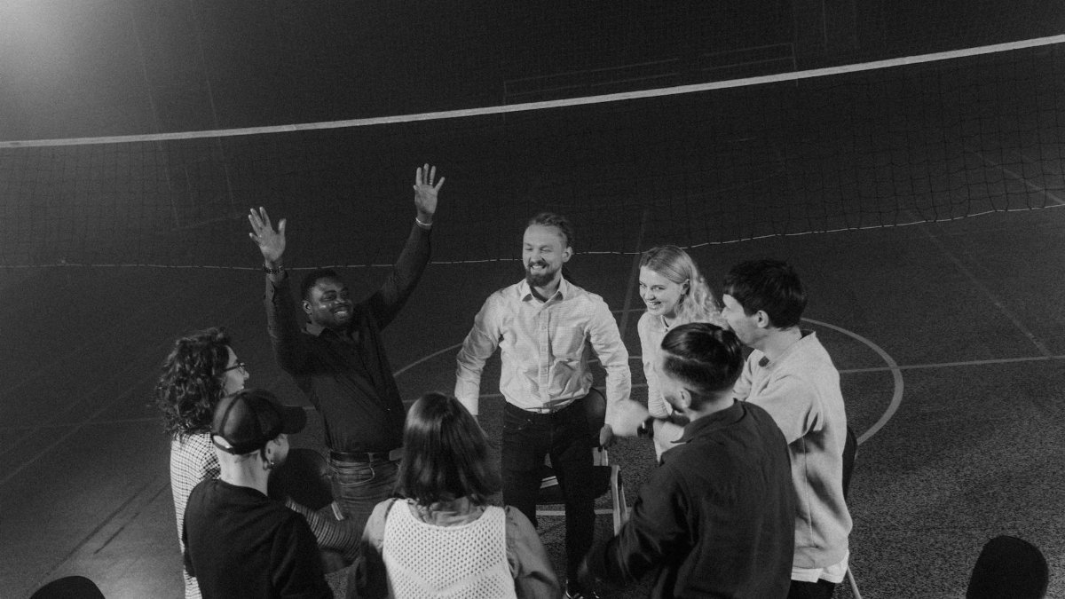 A diverse group of people in a team building huddle indoors, fostering togetherness and support.