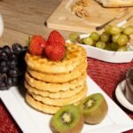 Tasty breakfast setup with waffles, fresh fruits, and cheese in a cozy setting.
