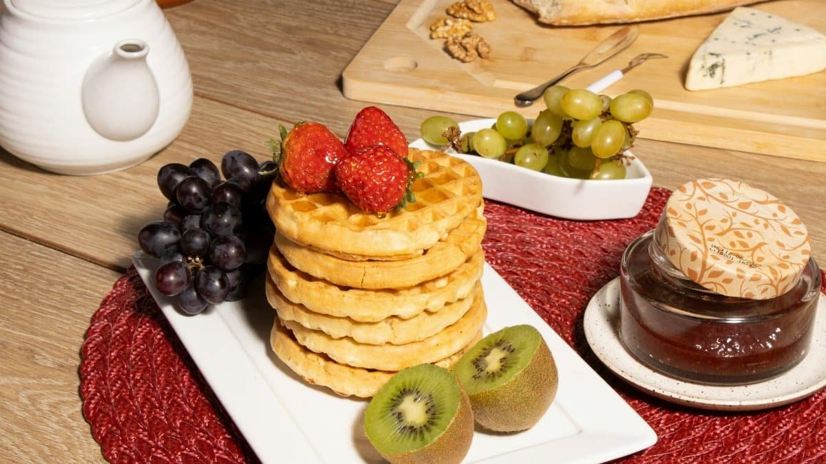 Tasty breakfast setup with waffles, fresh fruits, and cheese in a cozy setting.