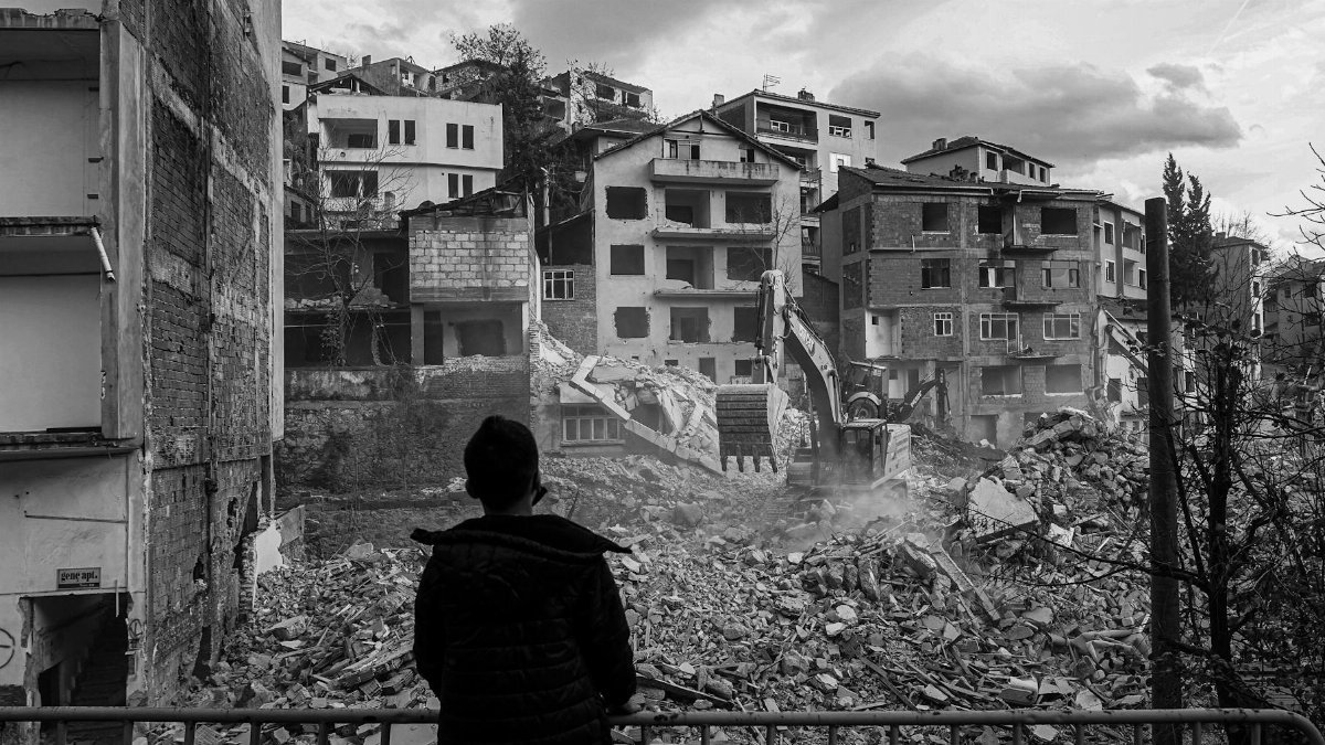 A person watches the demolition of dilapidated urban buildings.