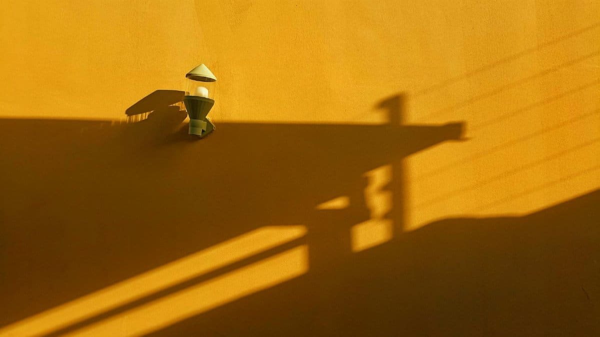 A minimalistic view of a yellow wall with light fixture casting shadows, captured in Jos, Nigeria.